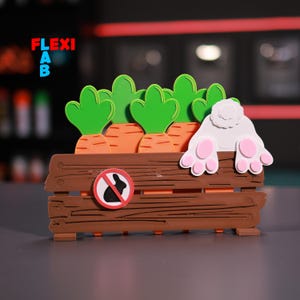 Pode incluir: Uma caixa de madeira com uma placa de "sem coelhos" e as patas traseiras de um coelho branco que sobressaem. A caixa está cheia de topos de cenoura verdes e cenouras laranja.