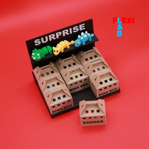 Puede incluir: Un expositor con un letrero negro que dice "SURPRISE" y tres figuras de dinosaurios de colores. Debajo hay varios paquetes "DINO BOX", con una caja etiquetada "DANGER". El fondo es rojo liso.