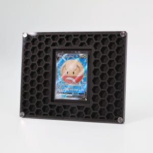 May include: Black acrylic display stand with a honeycomb pattern and a clear plastic insert for a trading card. The card shows a Pokemon character named "Lectrobel" with the number "210".