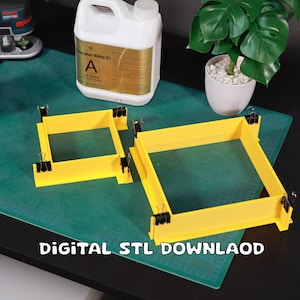 Puede incluir: Dos marcos cuadrados de plástico amarillo con clips negros sobre una estera de corte verde. Los marcos son para hacer moldes. El texto "DIGITAL STL DOWNLOAD" está en la estera.