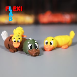 May include: Three small rubber duck figurines. One duck is green with brown eyes and a brown beak. The other two ducks are yellow with orange beaks and black eyes.