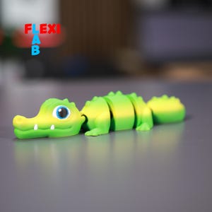 May include: A green and yellow segmented crocodile toy with a blue eye. The toy is made of flexible plastic and can be bent and posed.