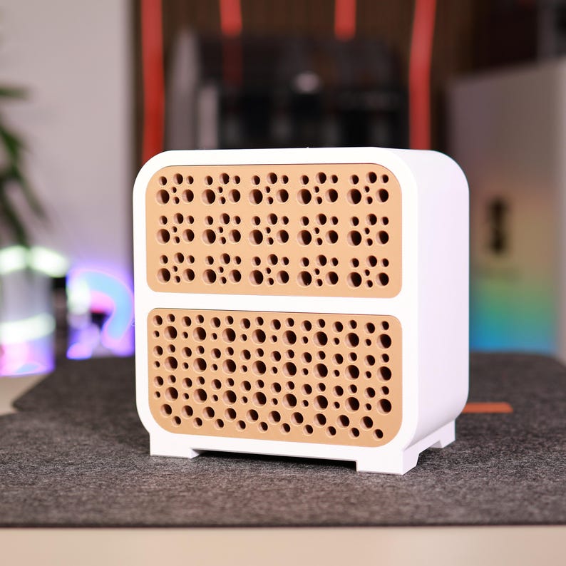 K&ouml;nnte beinhalten: Ein wei&szlig;er Aufbewahrungsschrank mit zwei Schubladen und perforierten beigefarbenen Paneelen. Der Schrank hat ein modernes Design mit abgerundeten Kanten und einem stabilen Sockel. Die perforierten Paneele sind mit kleinen, gleichm&auml;&szlig;ig verteilten L&ouml;chern gef&uuml;llt.