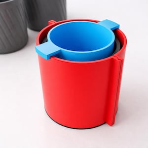Peut inclure: Un cendrier rouge et bleu au design cylindrique. Le cendrier a un ext&eacute;rieur rouge vif, un int&eacute;rieur bleu et deux languettes bleues. Le cendrier est fait d'un mat&eacute;riau lisse et brillant.