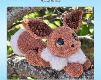 May include: A brown and white crocheted fox plush toy with large ears and sparkling eyes, resting on a tree branch. The image includes the text "Floof Fox Sploot Series" and "PDF Crochet Pattern".