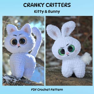 May include: Two white crochet critters: a cat and a bunny. The cat has a long tail and is perched on a branch. The bunny has long ears and a fluffy tail. Both have large, expressive eyes and a grumpy expression. The text "CRANKY CRITTERS Kitty & Bunny" is at the top.