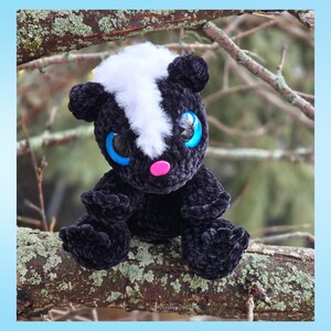 May include: A handmade plush skunk with black, white, and pink details. The skunk has large blue eyes and is sitting on a tree branch. The plush toy is made of soft, textured material.