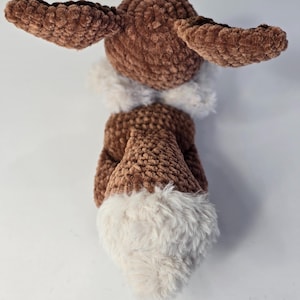 May include: A handmade brown plush toy with a white fluffy trim. The toy has large, textured ears and a fluffy tail. The plushie is made of soft, velvety material, perfect for cuddling. The toy is designed to resemble a woodland creature.