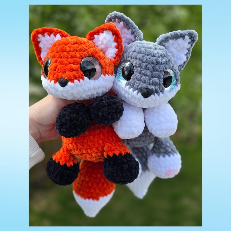Puede incluir: Dos peluches de zorro y lobo tejidos a crochet. El zorro es naranja con detalles blancos y negros, y el lobo es gris con detalles blancos y negros. Ambos tienen ojos grandes y brillantes.