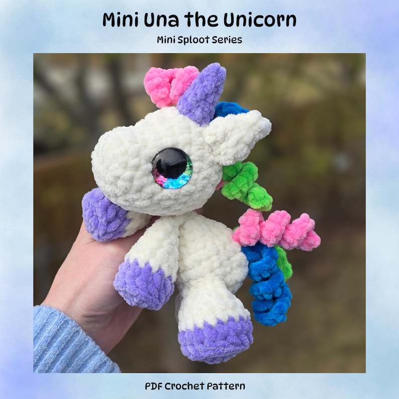 May include: A handmade white crochet unicorn plushie with purple hooves and accents. The unicorn has a rainbow mane and tail, and large, colorful eyes. The text "Mini Una the Unicorn" and "Mini Sploot Series" are visible.
