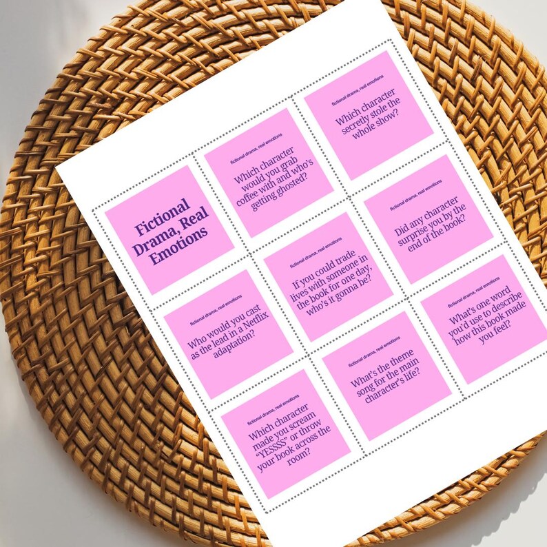 Puede incluir: Una hoja de papel blanca con cuadrados rosas que contienen preguntas sobre libros, titulada "Fictional Drama, Real Emotions". El papel est&aacute; sobre una superficie de mimbre tejido. Las preguntas incluyen "&iquest;Con qu&eacute; personaje tomar&iacute;as caf&eacute;?" y "&iquest;Cu&aacute;l es la canci&oacute;n principal?"