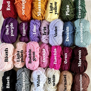 May include: A collection of yarn skeins in various colors, including red, orange, yellow, green, blue, purple, pink, white, brown, and black. The yarn is arranged in rows, with the colors alternating. The yarn is labeled with the color name.