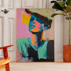 Op de afbeelding: Een kleurrijk abstract schilderij van een persoon met een hoed en zonnebril. Het kunstwerk gebruikt levendige kleuren zoals roze, geel, blauw en groen. Het schilderij wordt getoond in een kamer met een houten stoel en een plant in een pot.