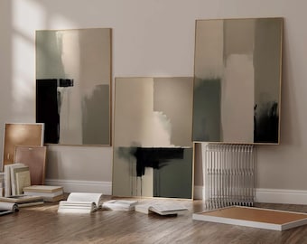 May include: Three abstract paintings with black, white, and green brushstrokes on a beige background. The paintings are framed in gold and hung on a white wall.