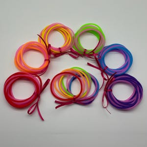 Juego de diez pulseras de gelatina de los años 80 en rosa, azul, verde, naranja, morado, arcoíris, rojo y amarillo, envueltas en un lazo de satén.