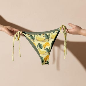 May include: A yellow and green bikini bottom with a banana print. The bikini bottom has adjustable ties on the sides.