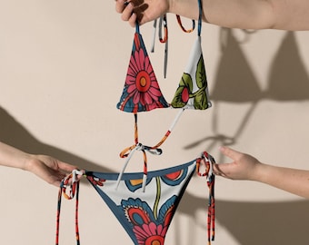 May include: A floral print bikini with a triangle top and a high-cut bottom. The bikini is in shades of blue, white, red, and green.