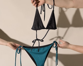 Puede incluir: Bikini negro y turquesa con una parte superior de triángulo y una parte inferior de corte alto. Ambas piezas tienen un pequeño patrón de puntos blancos.