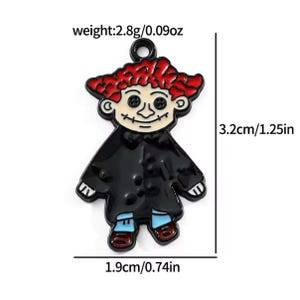 May include: A cartoon-style charm in the shape of a figure with red hair, black coat, and blue pants. The charm is 1.25 inches tall and 0.74 inches wide, weighing 0.09 ounces. The figure has a smiling face with button eyes.