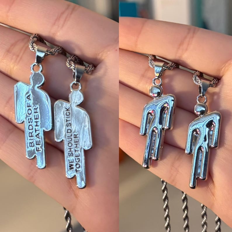 May include: Two silver-toned pendant necklaces. Each pendant is shaped like a person. One pendant reads "BIRDS OF A FEATHER" and the other reads "WE SHOULD STICK TOGETHER". The necklaces have a rope chain.