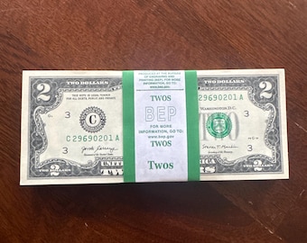 May include: A stack of United States two-dollar bills secured by a green paper band. The band features the text PRODUCED AT THE BUREAU OF ENGRAVING AND PRINTING (BEP), FOR MORE INFORMATION, GO TO: www.bep.gov, TWOS, BEP, TWOS, and Twos.