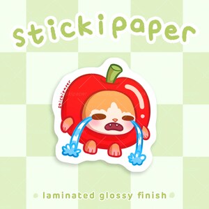 May include: A red apple sticker with a crying cartoon animal inside. The sticker has a glossy finish and says "stickipaper" at the top.