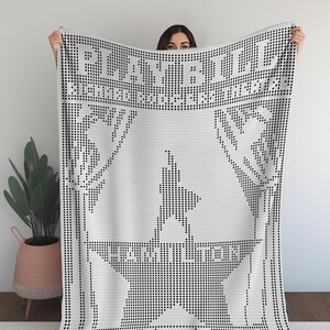May include: A white blanket with a black dot pattern. The blanket features the text "PLAYBILL" at the top and "HAMILTON" in the center, along with a star and silhouette design. The blanket is made of a soft material.