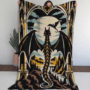 May include: A rectangular throw blanket featuring a pixelated design of a large black dragon with spread wings standing before a full moon. The scene includes gothic architectural arches, a smaller flying dragon, and a landscape of mountains.