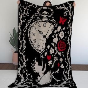 May include: A black rectangular throw blanket featuring a pixelated design in cream and red. The pattern displays a large pocket watch, a red rose, a red butterfly, a red heart, a key, and card suit symbols, all framed by thorny branches.