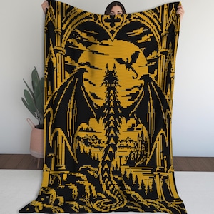 Peut inclure: Un plaid rectangulaire présentant un motif en pixel art noir et doré. Le dessin représente un grand dragon aux ailes déployées devant une pleine lune, encadré par des arches architecturales gothiques et un paysage d'arbres en bas.