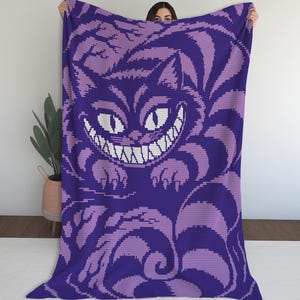 May include: A rectangular throw blanket featuring a pixelated graphic of a grinning cat with large eyes and sharp teeth. The design uses a two-tone color palette of deep purple and light lavender, depicting the cat amidst stylized foliage patterns.