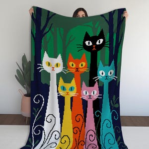 Könnte beinhalten: Eine farbenfrohe Häkeldecke mit sechs stilisierten Katzen vor einem Waldhintergrund. Die Katzen sind in verschiedenen Farben: Weiß, Orange, Gelb, Rosa, Schwarz und Blau. Die Decke hat einen dunkelgrünen Rand und ein weißes Blumendesign.