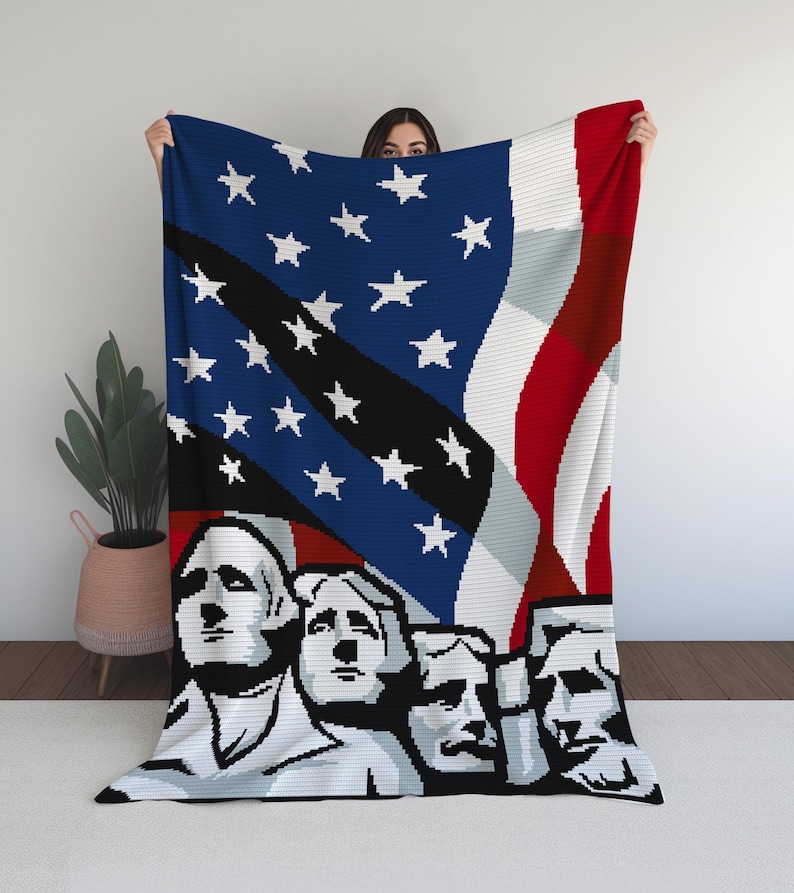 K&ouml;nnte beinhalten: Eine patriotische Decke mit der amerikanischen Flagge und Mount Rushmore. Die Decke hat ein blaues Feld mit wei&szlig;en Sternen, rot-wei&szlig;en Streifen und eine Schwarz-Wei&szlig;-Darstellung des Pr&auml;sidentendenkmals. Die Decke wird von einer Person gehalten.