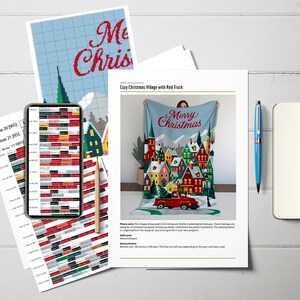 May include: A light blue blanket with a "Merry Christmas" design, featuring a cozy village scene with a red truck. The image also includes a smartphone displaying a pattern, a pen, and printed instructions for a crochet project.