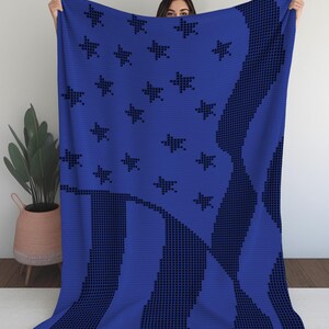 Pu&ograve; includere: Una coperta blu con un disegno che ricorda la bandiera americana. La coperta presenta stelle e strisce blu scuro su uno sfondo blu vibrante. Le stelle e le strisce sono create con un effetto pixelato.