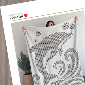 May include: A white blanket with a black dolphin design. The blanket features a filet crochet pattern with the words "Dolphin Love" at the top. The design includes a dolphin, bubbles, and waves.