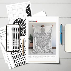 May include: A white blanket with a black sea turtle mandala design is displayed. The image includes a smartphone showing a pattern, printed pattern sheets, a pencil, a blue pen, and a notebook. The text "Sea Turtle Mandala" is visible.