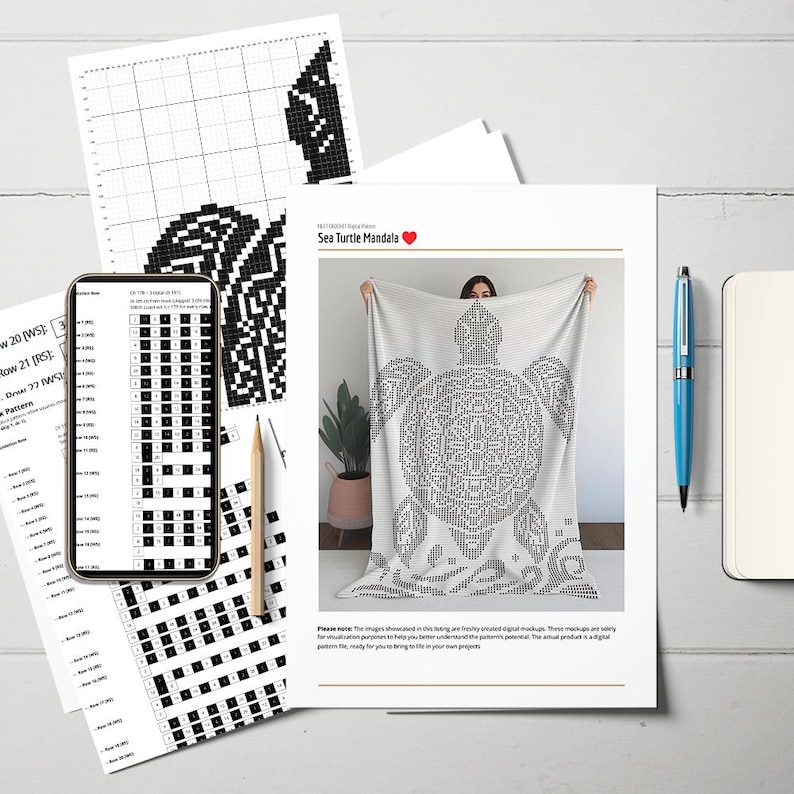 May include: A white blanket with a black sea turtle mandala design is displayed. The image includes a smartphone showing a pattern, printed pattern sheets, a pencil, a blue pen, and a notebook. The text "Sea Turtle Mandala" is visible.