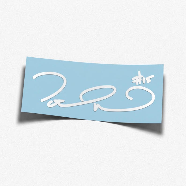 May include: A rectangular light blue sticker featuring a white stylized signature and the text #15. The design consists of fluid, looping white lines that form a cursive-style autograph, positioned centrally on the light blue background.