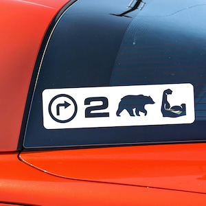 May include: White decal with a black circle containing a right arrow, the number "2", a black bear silhouette, and a black silhouette of a bicep flexing.