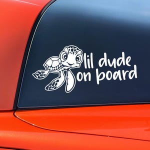 May include: A white vinyl sticker with a cartoon turtle and the text "lil dude on board".