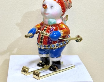 Adorable skiing snowman figurine with bright enamel colors—perfect for Christmas décor, gifting, holiday collections or charm to any space