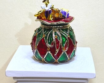 Charming Christmas gift bag loaded with presents, finished in vibrant enamel and gold accents. A delightful holiday décor and sweet gift