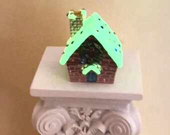 Christmas cottage décor with glow-in-the-dark sparkling snowy rooftop and wreath details. Cozy holiday house perfect for gifting or display