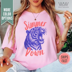 May include: Pink t-shirt with a blue and white tiger graphic and the text "Summer Down" in pink.