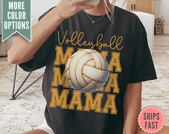 Może przedstawiać: Czarny T-shirt z napisem "Volleyball Mama" złotymi literami i grafiką białej piłki siatkowej.