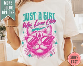 May include: White t-shirt with a pink cat wearing sunglasses and the text "Just a Girl Who Loves Cats" in turquoise and pink.
