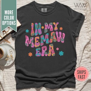 Könnte beinhalten: Schwarzes T-Shirt mit einer bunten Grafik, auf der "In My Memaw Era" mit Blumen um den Text steht.