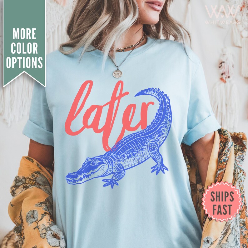 May include: Light blue t-shirt with a blue alligator and the word "later" in red.