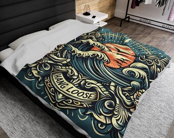 May include: A blue and yellow throw blanket with a graphic design of a wave, sun, and the text "Hang Loose".